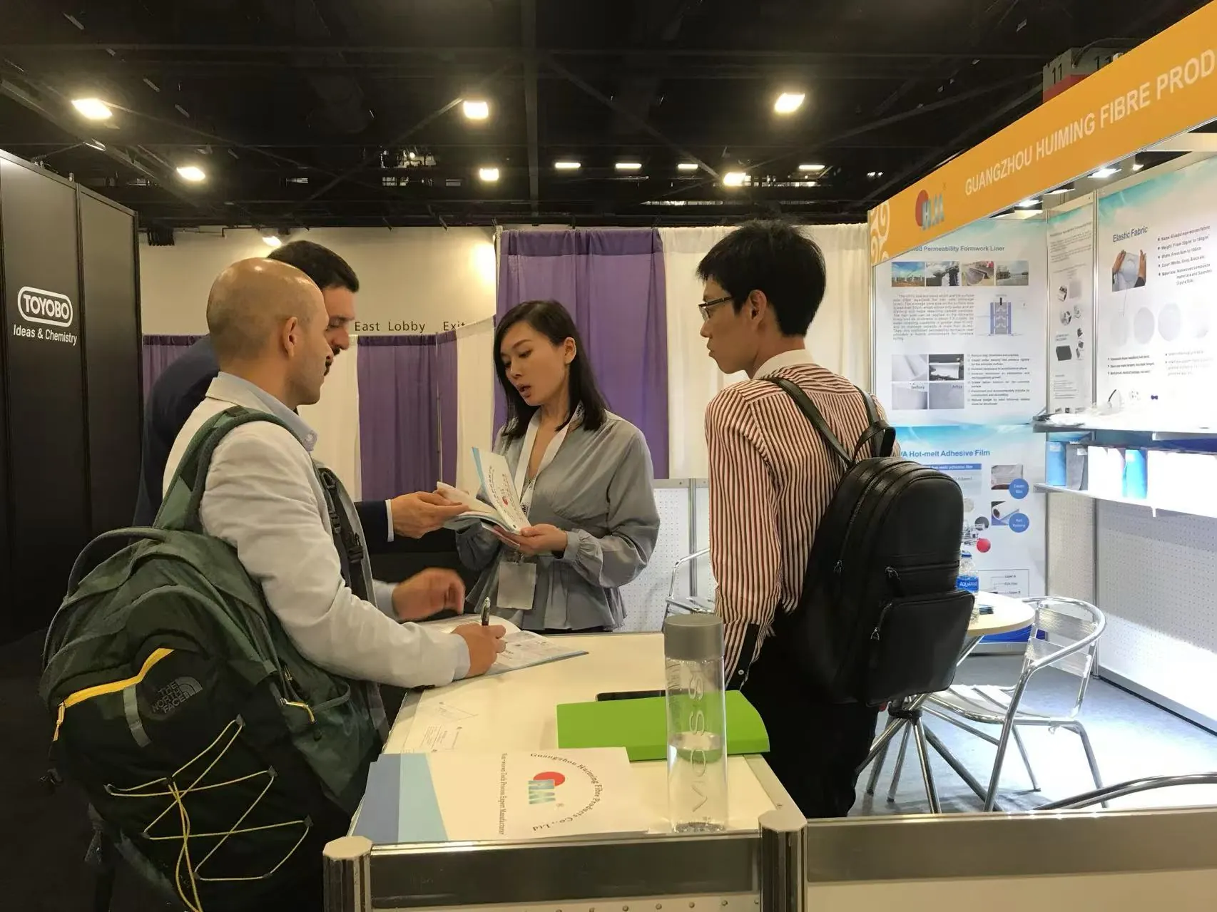 Exhibition booth technical conversation with multiple visitors